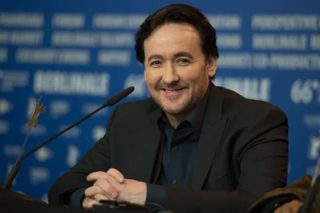 John Cusack is a name synonymous with relatable characters, quirky charm, and a filmography that has brought joy to audiences for over four decades. But Cusack's impact goes beyond box office success. He's a versatile actor, a dedicated producer, and a writer who isn't afraid to take risks. Early Life and Stepping into the Spotlight (1966-Present) Born in Evanston, Illinois in 1966, John Cusack comes from a creative family. His father, Dick Cusack, is a filmmaker, and his sisters, Joan and Ann Cusack, are both successful actresses. It's no surprise then, that Cusack began acting at a young age. His professional career kicked off in the early 1980s, and by the mid-80s, he was a rising star. The Breakout Years: From Teen Angst to Enduring Classics (1980s-1990s) The 1980s saw Cusack become a fixture in teen coming-of-age films. Who can forget his iconic roles in "Sixteen Candles," "Better Off Dead," and the ever-quoted "Say Anything..."? These films showcased his comedic timing and ability to connect with audiences on a personal level. As the 90s arrived, Cusack's career took a more diverse turn. He transitioned seamlessly into more dramatic roles, captivating audiences in films like "Bullets Over Broadway," "The Shawshank Redemption" (though his scenes were ultimately cut), and the critically acclaimed "The Thin Red Line." Beyond the Leading Man: Exploring Indie Films and Genre-Bending Roles (1990s-Present) Cusack has never been afraid to push boundaries. He embraced independent cinema, starring in thought-provoking films like "Being John Malkovich" and "High Fidelity," both of which garnered him critical acclaim and solidified his place as a Hollywood heavyweight. His ability to switch between genres is another hallmark of his career. From action thrillers like "Con Air" to romantic comedies like "America's Sweethearts," Cusack consistently delivers memorable performances. More Than Just Acting: A Multifaceted Creative (1990s-Present) Cusack's talents extend beyond acting. He's a passionate writer and producer, often collaborating on projects that reflect his own creative vision. This dedication to storytelling further cements his place as a well-rounded artist. A Look at His Net Worth and Enduring Legacy (2024) With a successful career spanning four decades, it's no wonder John Cusack's net worth is estimated to be around $50 million according to CelebrityNetWorth. But his true legacy lies in the characters he's brought to life and the impact he's had on audiences. John Cusack: Still Going Strong John Cusack remains an active force in Hollywood. He continues to take on diverse roles and advocate for causes he believes in. Whether it's portraying a political activist in "14 Days in July" or lending his voice to animated films, Cusack's dedication to his craft is undeniable.